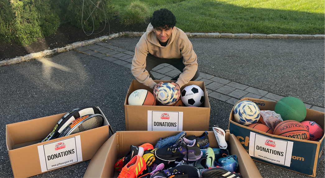 Volunteers loading boxes of donated sports gear — balls, shoes, and jerseys — into the back of a car